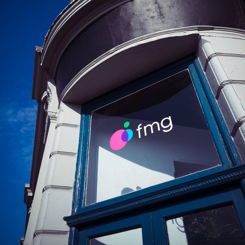 The FMG logo in the curved bay window of the Clarendon Mansions office, against a deep blue sky
